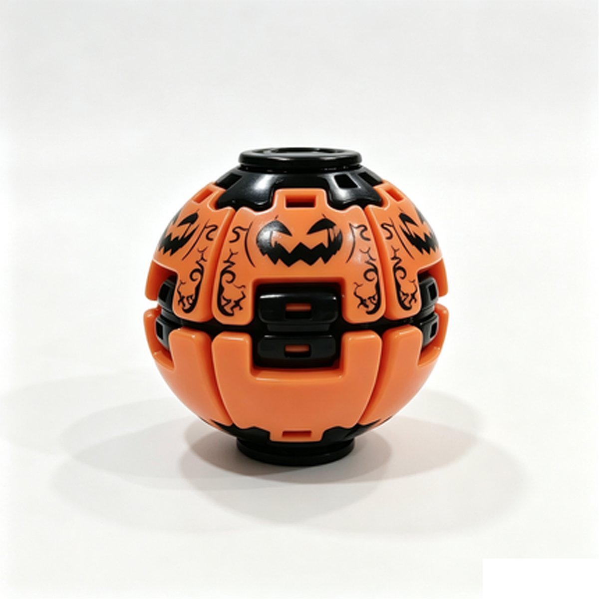 An orange and black spherical toy or decorative ball with carved jack-o'-lantern faces and decorative black patterns, photographed on a clean white background.
