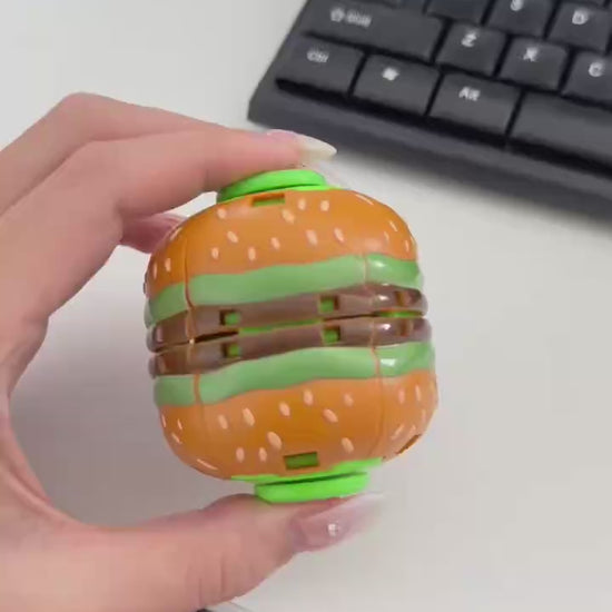 Hand demonstrating how to press and spin a burger fidget ball
