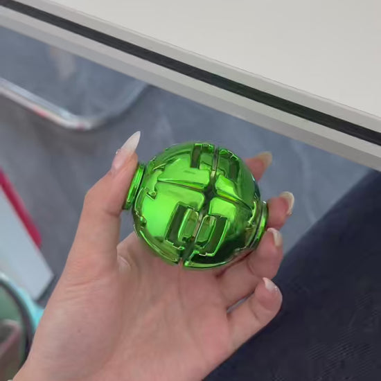 Video demonstration of a green metallic press spin fidget ball being handled and rotated.
