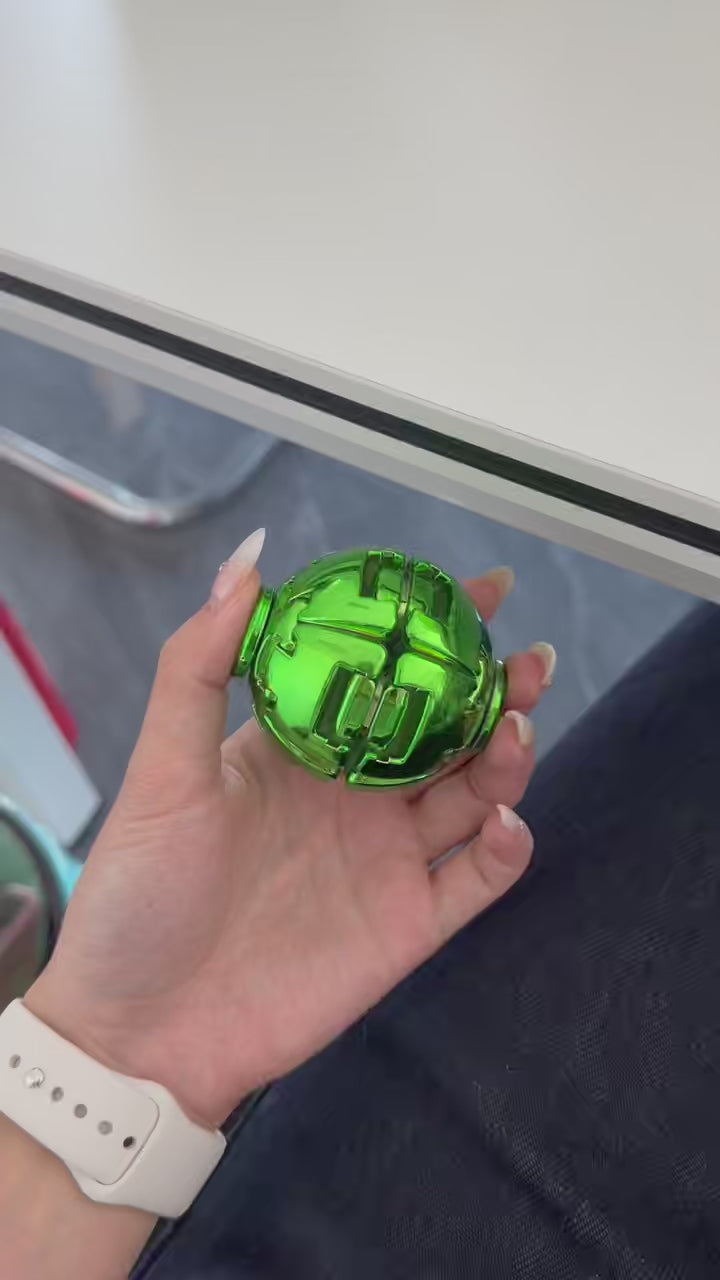 Video demonstration of a green metallic press spin fidget ball being handled and rotated.
